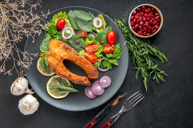 Free photo top view tasty cooked fish with fresh vegetables and seasonings on a dark table