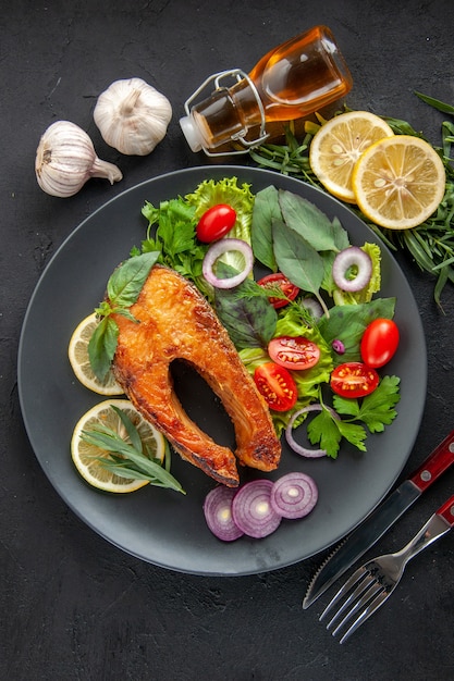 Free photo top view tasty cooked fish with fresh vegetables and seasonings on dark table