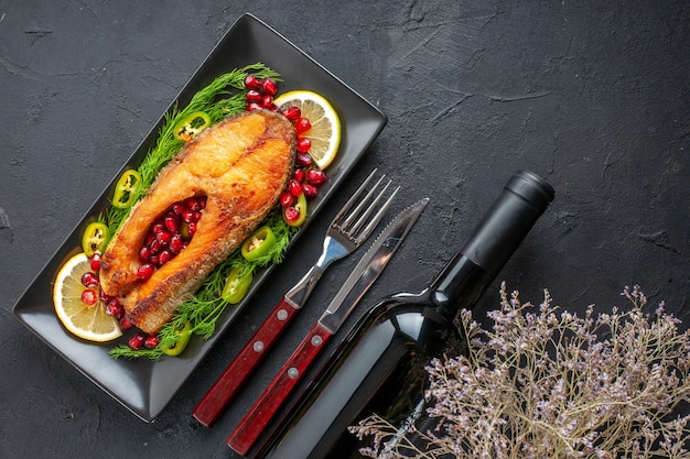 Free photo top view tasty cooked fish with greens and lemon slices inside pan on dark table