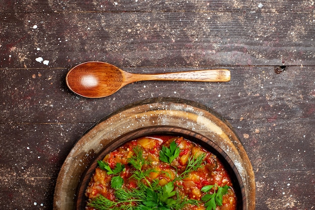 Free photo top view tasty cooked meal consists of sliced vegetables and greens on brown rustic desk meal sauce soup food vegetable calorie