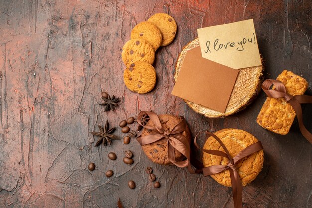 Top view tasty cookies tied with rope biscuits anises love letter on dark red table with