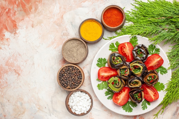 Top view tasty eggplant rolls with greens tomatoes and seasonings