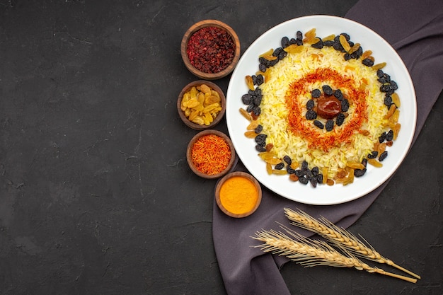 Free Photo top view tasty famous eastern meal consists of cooked rice and raisins on dark