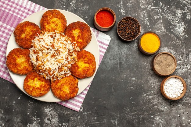 Top view tasty fried cutlets with rice and seasonings on a dark surface food meat rissole