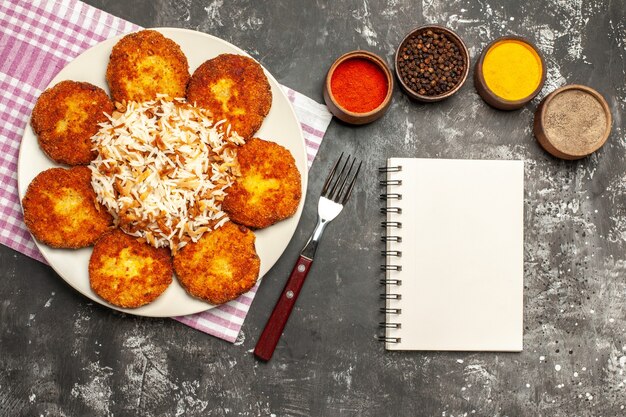 Top view tasty fried cutlets with rice and seasonings on a dark surface meat rissole food