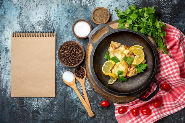 Top view tasty fried fish with lemon and parsley in pan on wood board