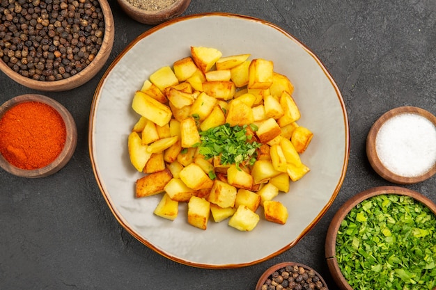 Free Photo top view of tasty fried potatoes inside plate with seasonings on dark surface