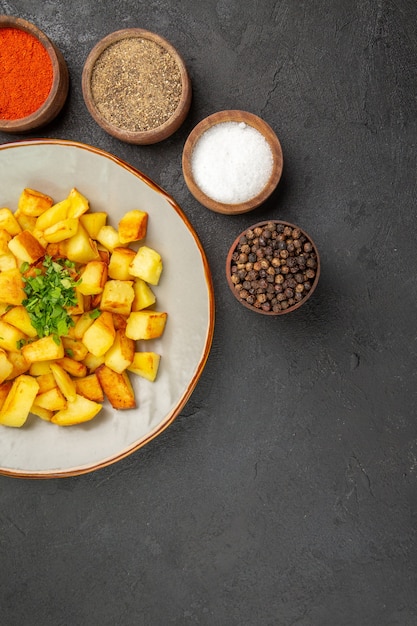 Free Photo top view of tasty fried potatoes inside plate with seasonings on dark surface