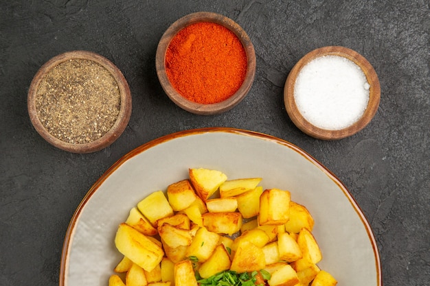 Free Photo top view of tasty fried potatoes inside plate with seasonings on dark surface