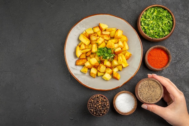 Free Photo top view of tasty fried potatoes inside plate with seasonings on dark surface