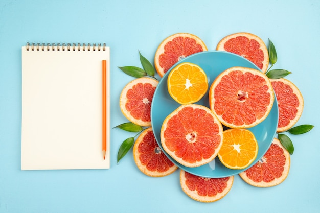 Free photo top view of tasty grapefruits fruit slices on blue surface