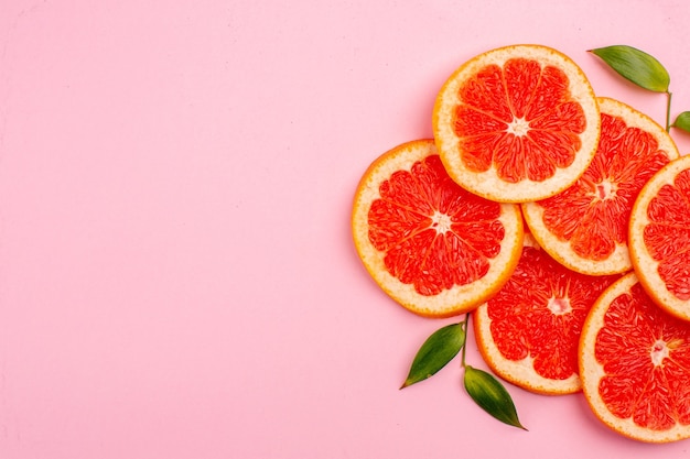 Top view of tasty grapefruits juicy fruit slices on pink surface