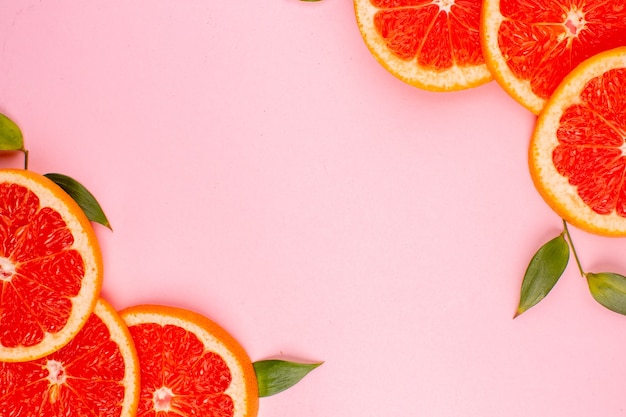 Top view of tasty grapefruits on pink surface