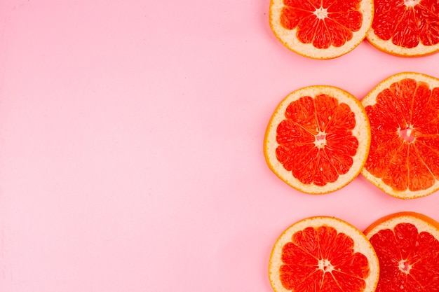 Top view of tasty grapefruits sliced juicy fruits on light pink surface