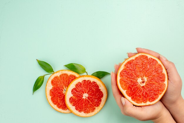 Top view of tasty grapefruits sliced juicy on light-blue surface