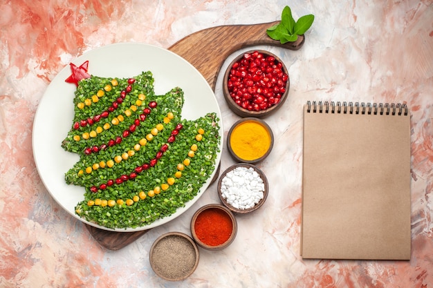 Free photo top view tasty holiday salad in new year tree shape with seasonings on light background