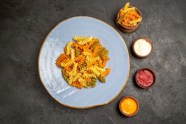 Free photo top view tasty italian pasta unusual cooked spiral pasta on grey