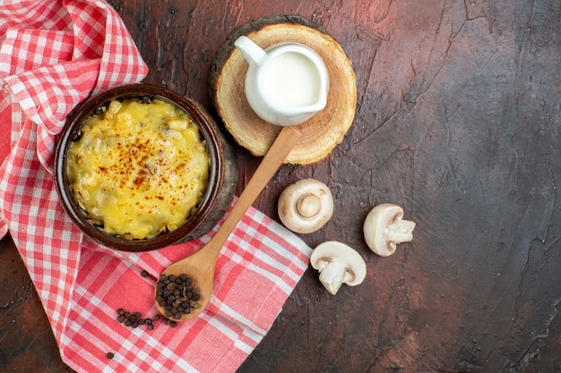 Free photo top view tasty julienne in bowl raw mushrooms milk bowl on wood board black pepper in wooden spoon red and white checkered kitchen towel on brown table