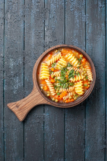 Free photo top view tasty pasta soup from spiral italian pasta with greens on a dark-blue desk cuisine dish italian pasta color soup