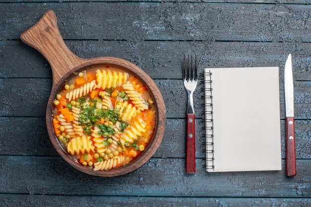 Free photo top view tasty pasta soup from spiral italian pasta with greens on the dark-blue desk soup dish color italian pasta cuisine