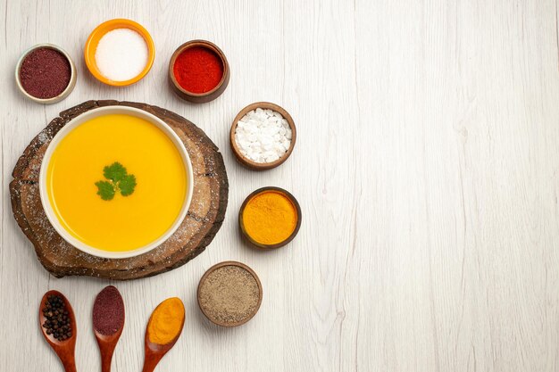 Top view of tasty pumpkin soup with different seasonings on white