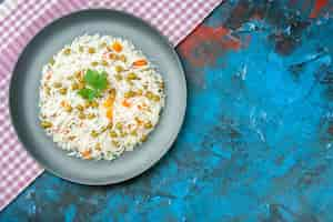 Free photo top view of tasty rice meal for dinner with pisum carrot on purple stripped towel on blue table