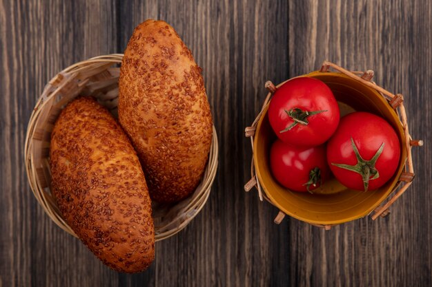 Top view of tasty sesame patties on a bucket with fresh red tomatoes on a bucket on a wooden background