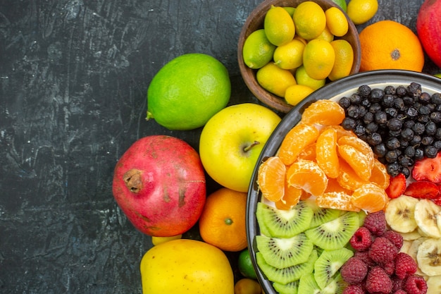 Top view tasty sliced fruits with fresh vegetables on gray background