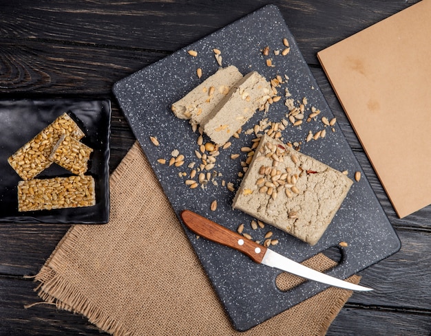 Free photo top view of tasty slices of halva with sunflower seeds on a black cutting board