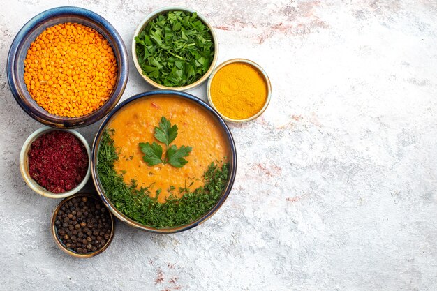 Top view tasty soup with different seasonings and greens on white surface meal food soup vegetables