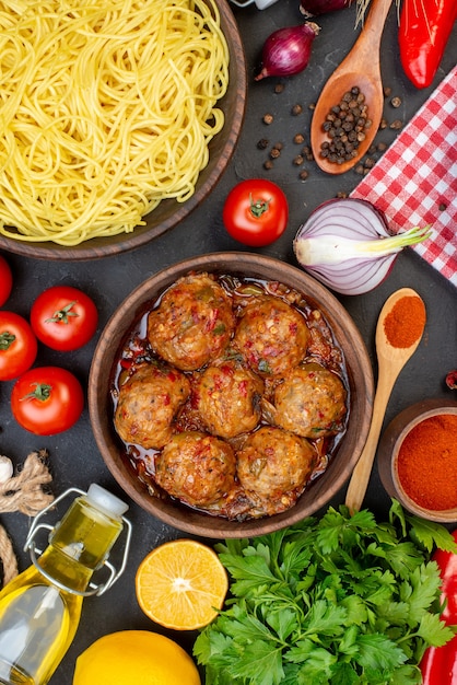 Free photo top view tasty spaghetti in bowl meatball in bowl oil bottle tomatoes parsley on table