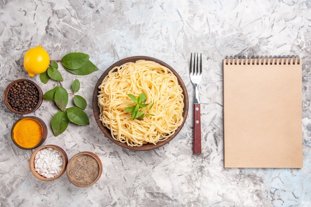 Free Photo top view tasty spaghetti with seasonings on a white dough meal dish pasta