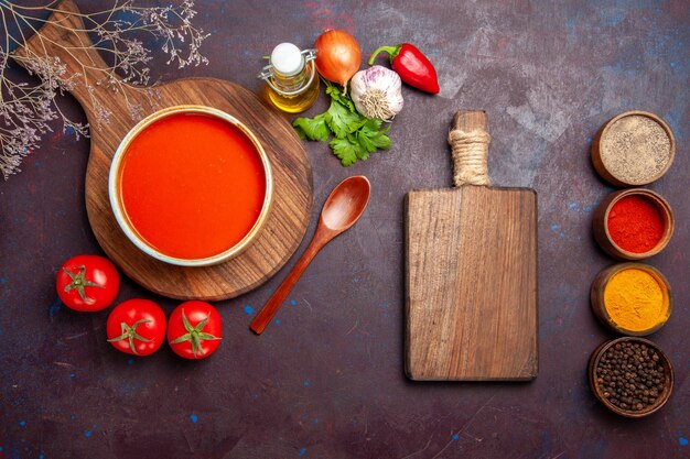 Top view of tasty tomato soup with seasonings on dark