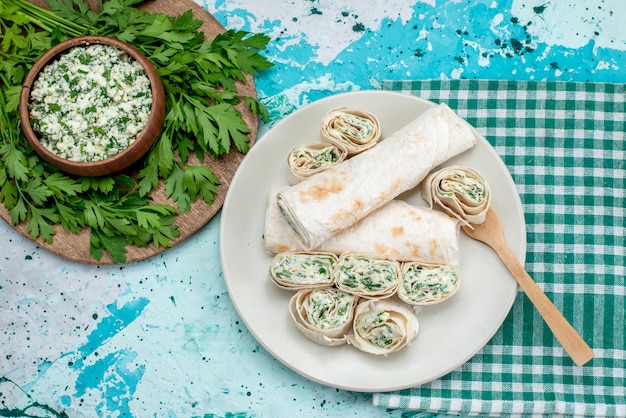 Top view tasty vegetable rolls whole and sliced with greens and salad on the blue table food meal roll vegetable color