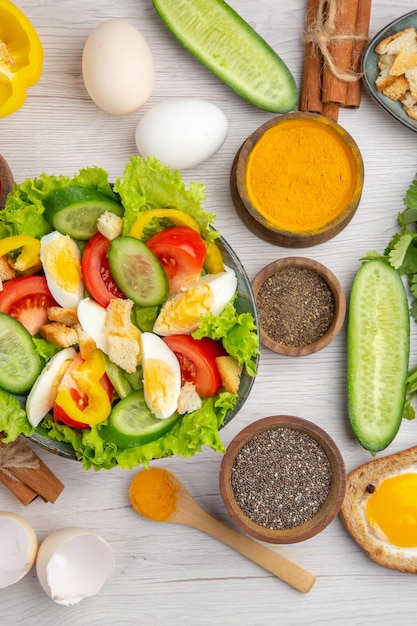 Top view tasty vegetable salad with eggs seasonings and tomatoes on the white background food color ripe breakfast lunch meal salad