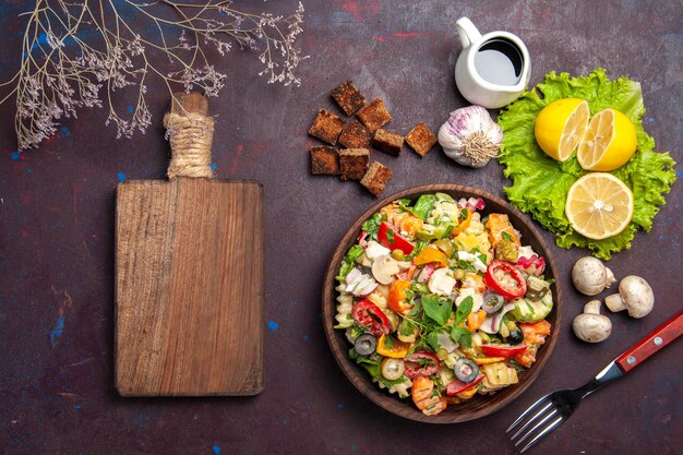 Top view of tasty vegetable salad with fresh lemon slices on black table