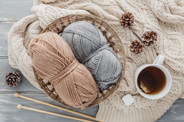 Free photo top view tea mug and yarn in basket with pine cones