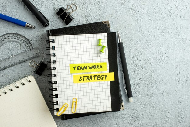 Free Photo top view of teamwork strategy writings on coloured sheets on spiral notebook and book ruler on gray sand background