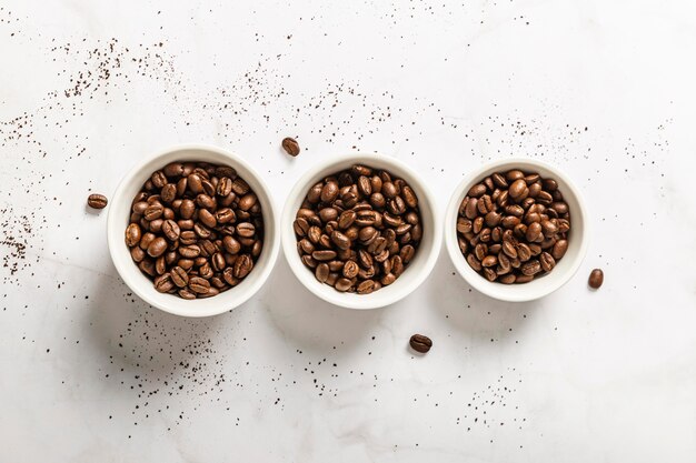 Top view of three cups with roasted coffee beans