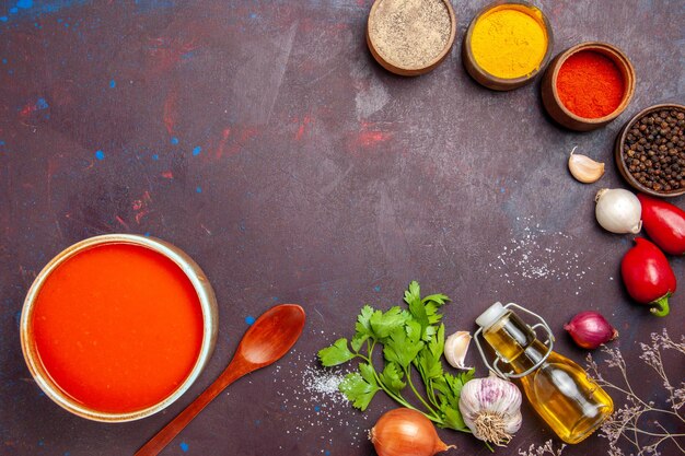 Top view of tomato soup cooked from fresh tomatoes with different seasonings on black