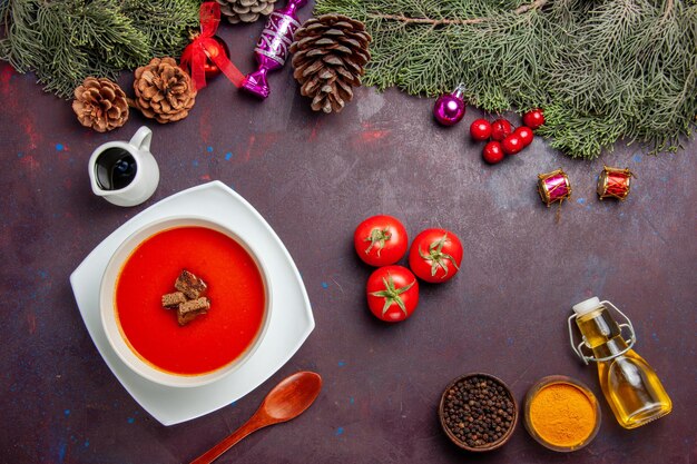 Top view of tomato soup with fresh tomatoes and seasonings on black