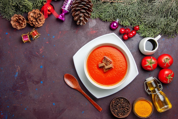 Top view of tomato soup with fresh tomatoes and seasonings on black