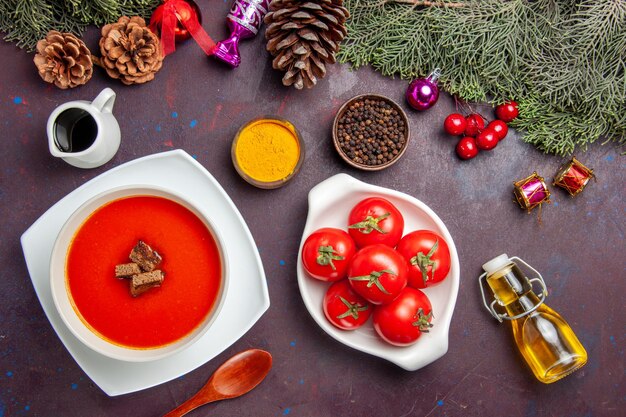 Top view of tomato soup with fresh tomatoes and seasonings on black