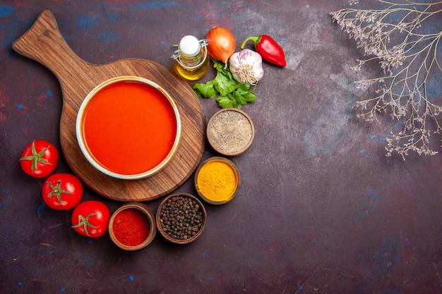 Top view of tomato soup with seasonings on black