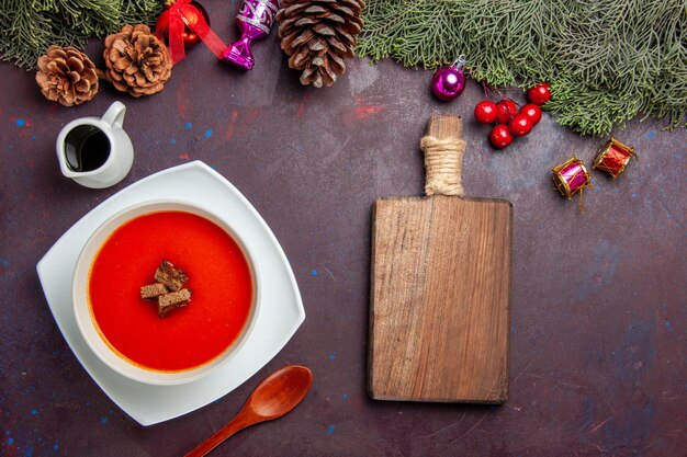 Top view of tomato soup with sliced bread inside on black