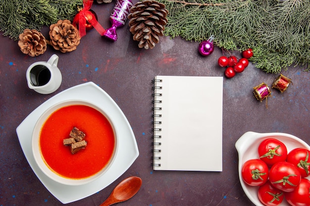 Top view of tomato soup with sliced bread inside on black