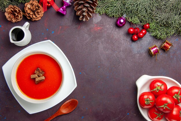 Top view of tomato soup with sliced bread inside on black