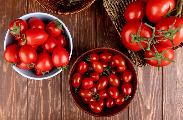 Top view of tomatoes in bowls and basket plate on wood