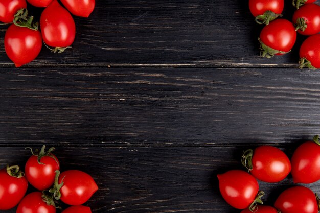 Top view of tomatoes on left and right sides and wooden surface with copy space