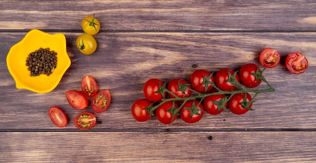 Top view of tomatoes with black pepper seeds on wood